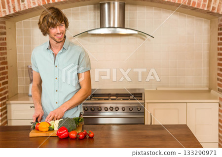 Man wearing green shirt chopping peppers broccoli cauliflower on kitchen countertop, copy space Man wearing green shirt chopping peppers broccoli cauliflower on kitchen countertop, copy space 133290971