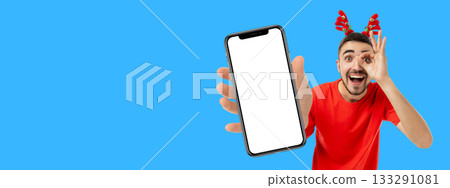 Young man in red shirt holds smartphone with blank screen 133291081