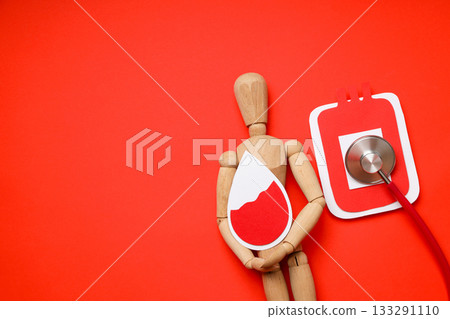 Mannequin holds a blood drop symbol next to a stethoscope 133291110
