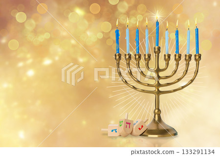 Menorah with blue candles and dreidels on a golden backdrop 133291134