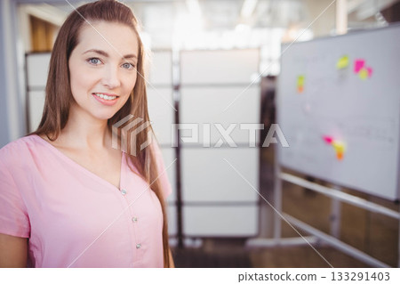 Professional in pink blouse smiling in open-plan office with whiteboard sticky notes, copy space Professional in pink blouse smiling in open-plan office with whiteboard sticky notes, copy space 133291403