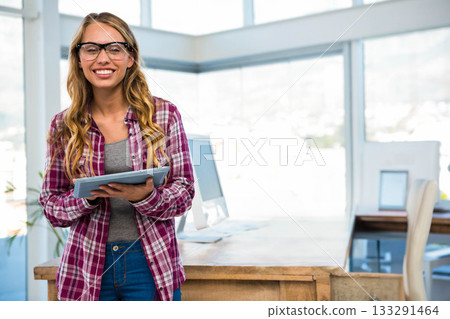 Female professional standing at office desk holding tablet wearing eyeglasses, copy space 133291464