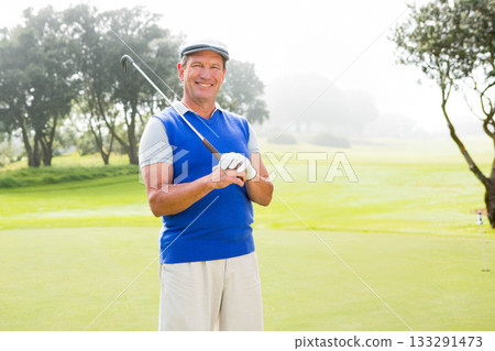 Senior African American man wearing vest holding iron golf club across chest on golf course green Senior African American man wearing vest holding iron golf club across chest on golf course green 133291473