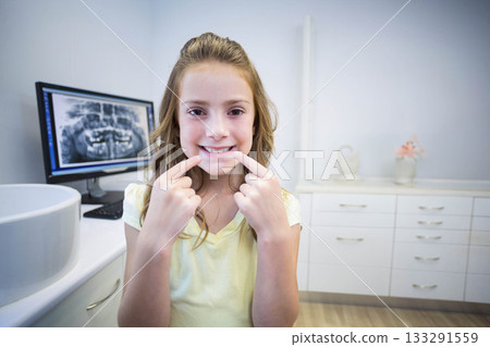 Child female patient pointing at lower teeth at dental clinic with computer monitor showing X-ray Child female patient pointing at lower teeth at dental clinic with computer monitor showing X-ray 133291559