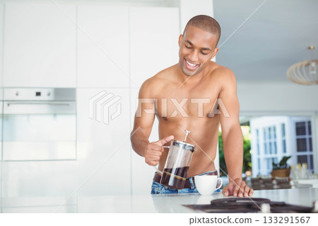 Shirtless African American man pouring French press coffee into mug in kitchen, copy space 133291567