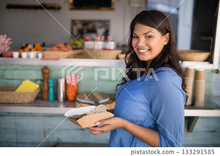Smiling woman holding tray with tortillas and salad at outdoor food truck counter, copy space Smiling woman holding tray with tortillas and salad at outdoor food truck counter, copy space 133291585