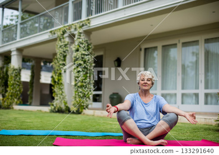 Woman meditating in activewear on pink yoga mat beside blue yoga mat on lawn, copy space Woman meditating in activewear on pink yoga mat beside blue yoga mat on lawn, copy space 133291640