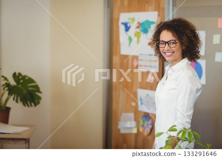 African American woman wearing shirt standing by board with world map in office, copy space 133291646