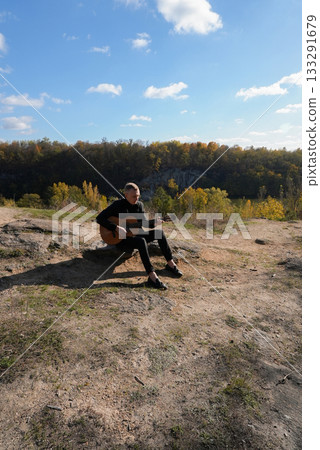 Blonde man playing string guitar outdoors in autumn forest. Concept of sound therapy, mental health and wellness rituals. Calmness tranquility audio-sensory practices. Aura farming energy Blonde man playing string guitar outdoors in autumn forest. Concept of sound therapy, mental health and wellness rituals. Calmness tranquility audio-sensory practices. Aura farming energy 133291679