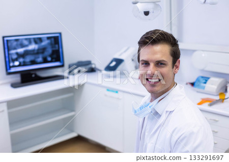 Male dentist standing by counter in treatment room with dental X-ray on monitor, copy space 133291697