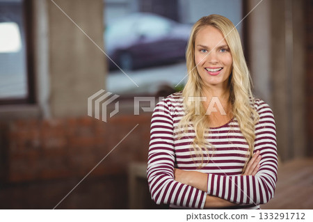 Woman wearing shirt smiling with folded arms in brick loft with industrial windows, copy space Woman wearing shirt smiling with folded arms in brick loft with industrial windows, copy space 133291712