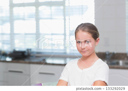 Girl standing with arms crossed in home kitchen beside granite countertop and blinds, copy space 133292029