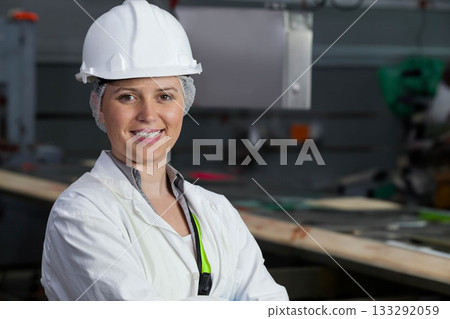 Female technician checking conveyor belt at factory wearing lab coat hairnet  and  hard hat, copy sp 133292059