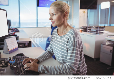 Coworkers typing on keyboard while checking monitor in office with large windows near desk phone Coworkers typing on keyboard while checking monitor in office with large windows near desk phone 133292063