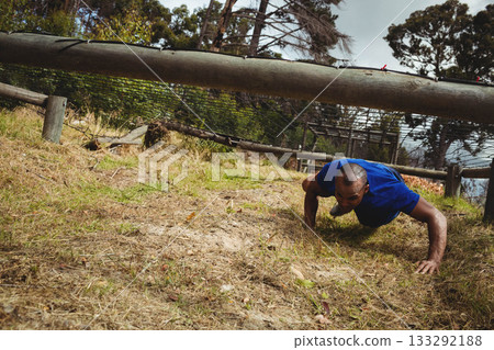 African American man crawling under barrier and fence on obstacle course in sportswear, copy space African American man crawling under barrier and fence on obstacle course in sportswear, copy space 133292188