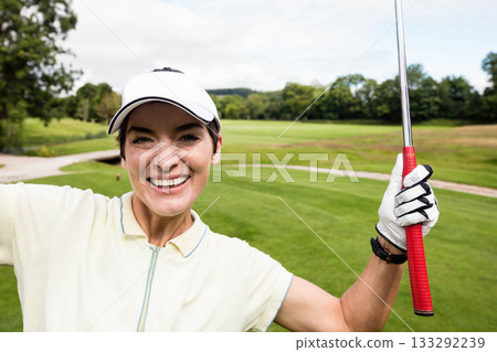 Senior female golfer raising red grip golf club on fairway while wearing white visor and glove Senior female golfer raising red grip golf club on fairway while wearing white visor and glove 133292239