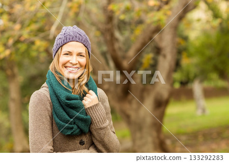 Woman standing in park in autumn wearing purple beanie green scarf and brown cardigan, copy space Woman standing in park in autumn wearing purple beanie green scarf and brown cardigan, copy space 133292283