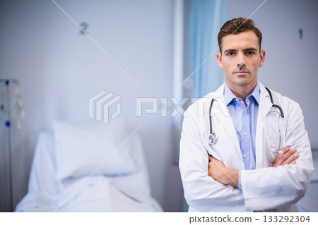 Male doctor wearing lab coat examining bed IV stand privacy curtain using stethoscope, copy space 133292304
