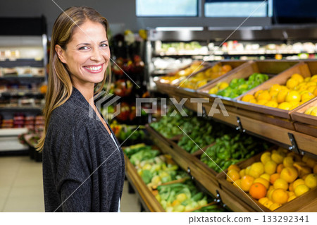 Woman in twenties smiling and browsing produce in supermarket aisle with racks and fridge shelves Woman in twenties smiling and browsing produce in supermarket aisle with racks and fridge shelves 133292341