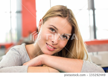 Teenage female student leaning on table in study lounge wearing gray top, hoops and bracelet 133292449