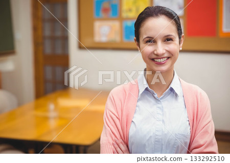 Female teacher standing arms folded beside wooden table and chairs in meeting room, copy space Female teacher standing arms folded beside wooden table and chairs in meeting room, copy space 133292510