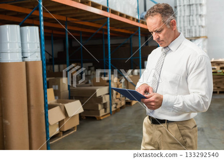 Male warehouse supervisor checking tablet while walking through racks and pallets, copy space Male warehouse supervisor checking tablet while walking through racks and pallets, copy space 133292540