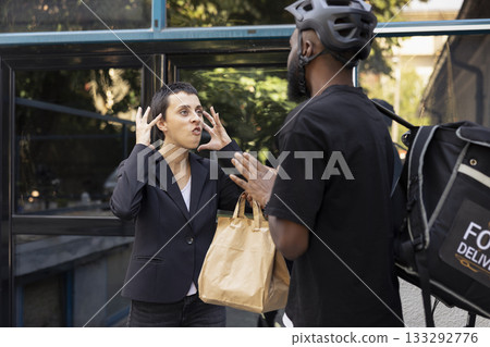 Upset client confronting delivery person after receiving the wrong meal, unhappy buyer gestures in protest with disappointment. Bad service from a busy restaurant takeaway, a mistake. Upset client confronting delivery person after receiving the wrong meal, unhappy buyer gestures in protest with disappointment. Bad service from a busy restaurant takeaway, a mistake. 133292776