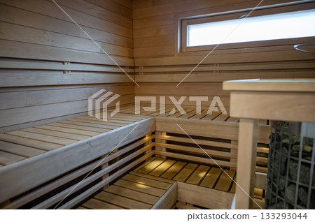 Empty modern wooden Finnish sauna interior with benches, warm lighting and clean design 133293044