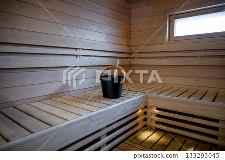 Traditional wooden Finnish sauna interior with bucket and ladle placed on warm benches 133293045