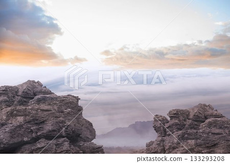 Jagged rocks in flat design are standing on summit revealing cloud inversion under pastel sky Jagged rocks in flat design are standing on summit revealing cloud inversion under pastel sky 133293208