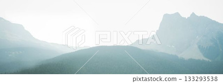Flat design panoramic mountain landscape displaying forested ridge and craggy peak under hazy sky 133293538