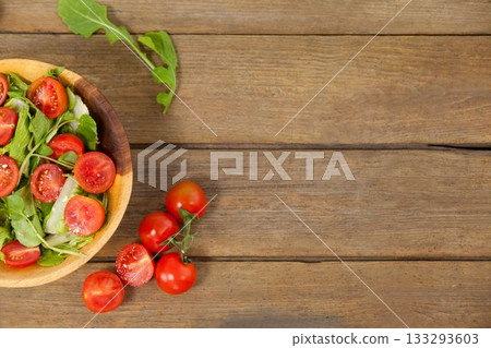 Fresh salad in bowl by tomatoes on wooden table Fresh salad in bowl by tomatoes on wooden table 133293603