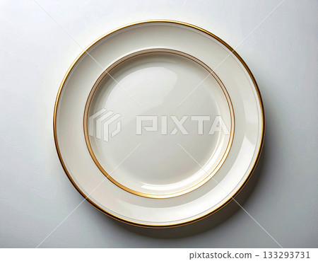 Classic elegance. Ceramic plate with a classic white and gold design on a white background. Porcelain kitchenware. Close-up. Top view. 133293731