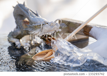 A beautiful winter scene of a frozen dragon and ladle at the Chozuya (water purification fountain) illuminated by the morning sun during the harsh winter in Otofuke Town, Hokkaido. A beautiful winter scene of a frozen dragon and ladle at the Chozuya (water purification fountain) illuminated by the morning sun during the harsh winter in Otofuke Town, Hokkaido. 133293742