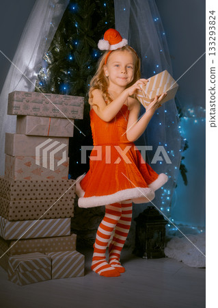 Holiday celebration with a girl in a red Santa outfit holding a Christmas gift surrounded by sparkling decorations. Holiday celebration with a girl in a red Santa outfit holding a Christmas gift surrounded by sparkling decorations. 133293824