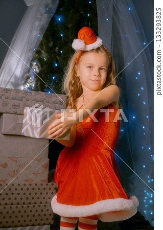 Elegant young woman dressed as Santa Claus enjoying the festive season next to a decorated Christmas tree. Elegant young woman dressed as Santa Claus enjoying the festive season next to a decorated Christmas tree. 133293825