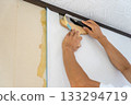 Cutting the edges of wallpaper with a cutter 133294719