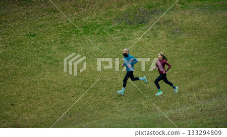 Runners keeping steady pace across open green hillside Runners keeping steady pace across open green hillside 133294809