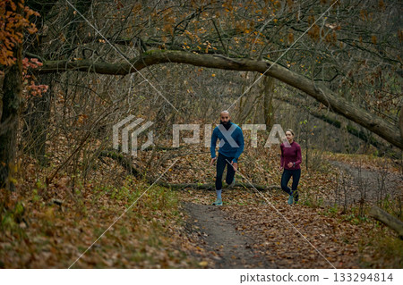 Two runners pushing uphill through dense autumn woods Two runners pushing uphill through dense autumn woods 133294814