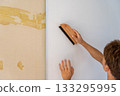 Carefully re-pasting wallpaper with a brush 133295995