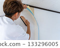 A man carefully replacing wallpaper 133296005