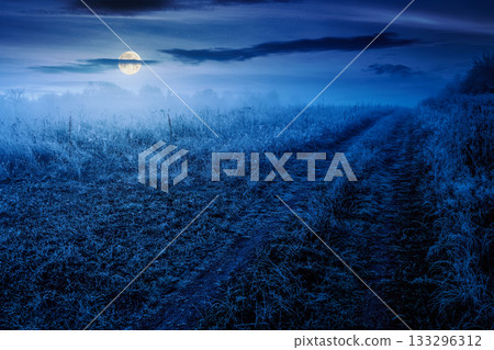 autumn landscape with dirt road through rural field in hoarfrost and fog at night. beautiful view of a countryside in mountains in full moon light. frosty weather. abandoned area needs investment autumn landscape with dirt road through rural field in hoarfrost and fog at night. beautiful view of a countryside in mountains in full moon light. frosty weather. abandoned area needs investment 133296312