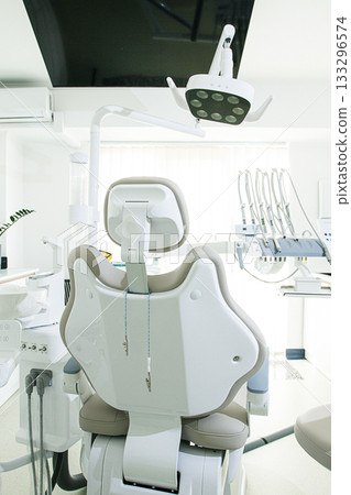 Modern dental clinic with a comfortable chair and equipment for patient care in a bright, clean environment Modern dental clinic with a comfortable chair and equipment for patient care in a bright, clean environment 133296574