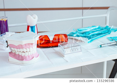 Various instruments, dental models, and hygiene items are laid out on the table in the dental office. natural light 133296586