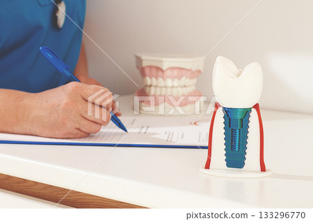 A dentist in a blue uniform studies patient information and prepares for treatment in a modern dental office A dentist in a blue uniform studies patient information and prepares for treatment in a modern dental office 133296770