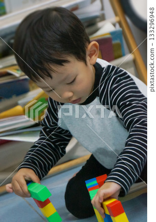 A focused child engrossed in playing with colorful blocks, a scene of creative building and developmental activity 133296948