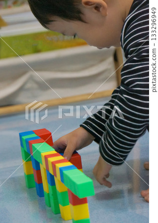 A child's hands building a structure using colorful blocks. This scene highlights creativity, learning, and play with colorful blocks. 133296949