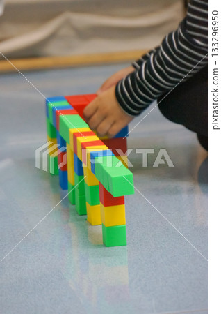 A child's hands building a structure using colorful blocks. This scene highlights creativity, learning, and play with colorful blocks. 133296950