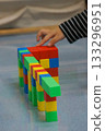 A child's hands building a structure using colorful blocks. This scene highlights creativity, learning, and play with colorful blocks. 133296951