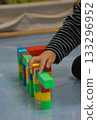 A child's hands building a structure using colorful blocks. This scene highlights creativity, learning, and play with colorful blocks. 133296952
